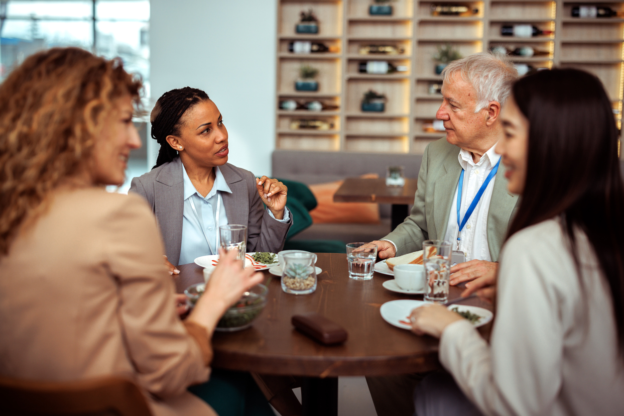 Group of well dressed business people talking during lunch break at the restaurant